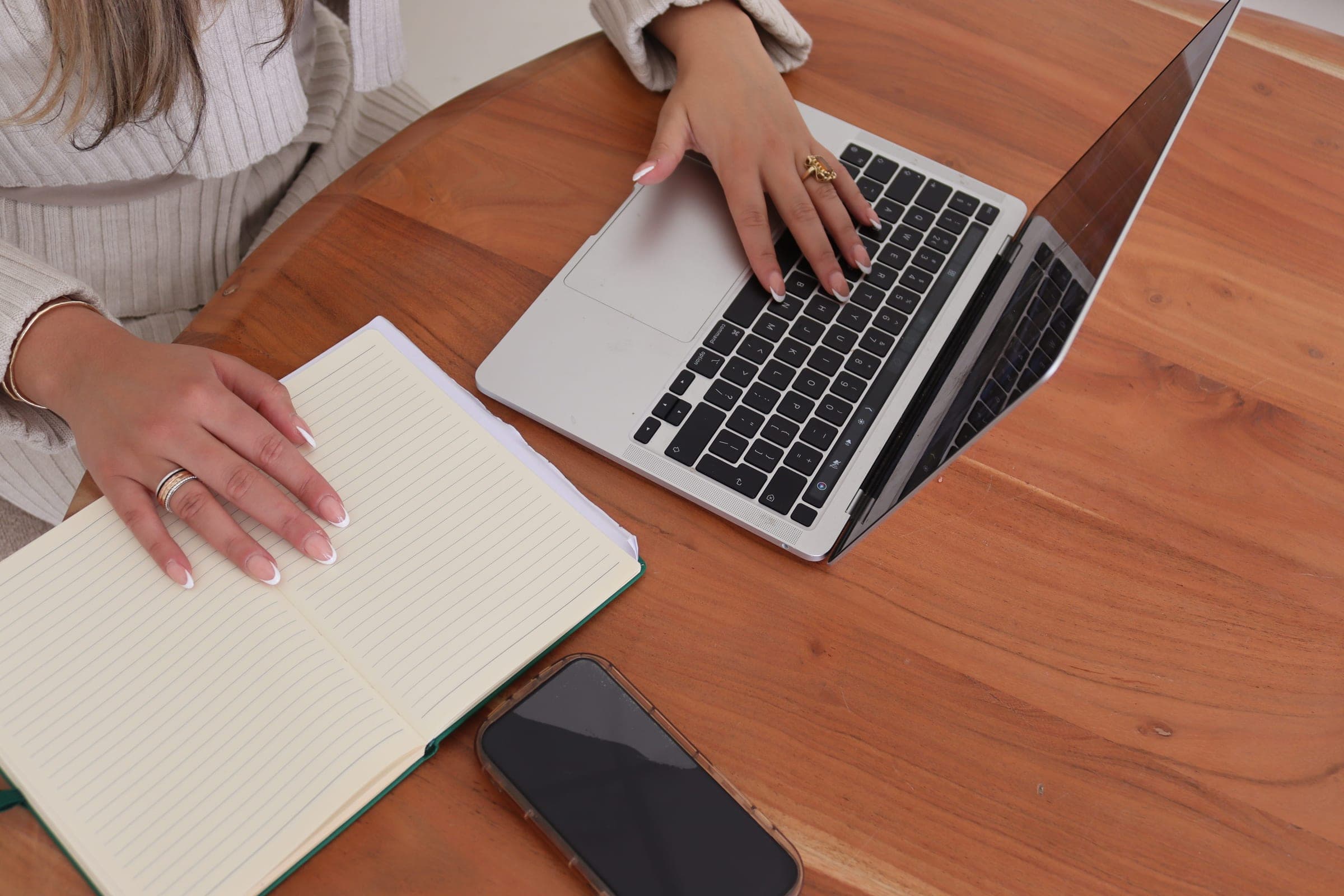 Laptop, notitieboek en telefoon op een houten tafel tijdens een accountanalyse